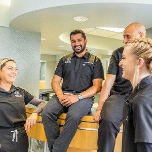 Group of dentists in black clothes laughing and smiling
