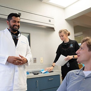 Dentist in white coat smiling at patient in dental chair