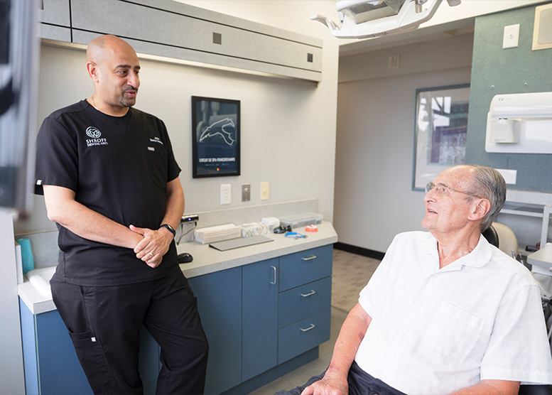 Dentist putting hand on smiling senior mans shoulder