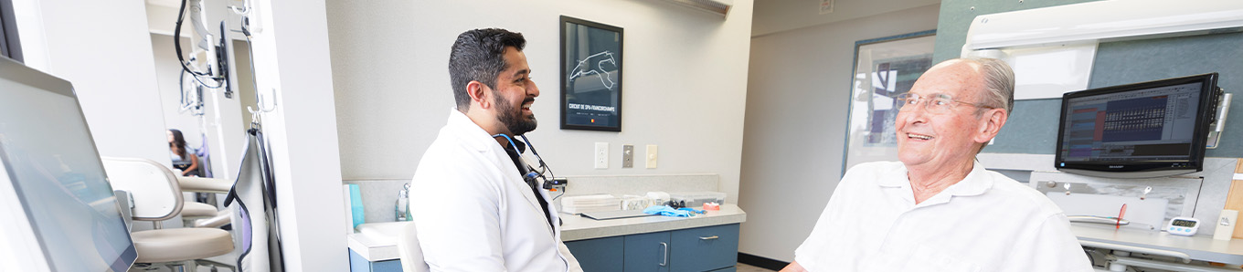 Man and woman smiling and talking to dentist in suit