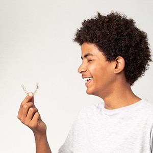 Teen with eyes closed smiling holding Invisalign