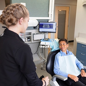 Teen in dental chair looking at dentist