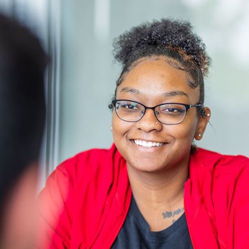 Woman smiling while taking notes during meeting