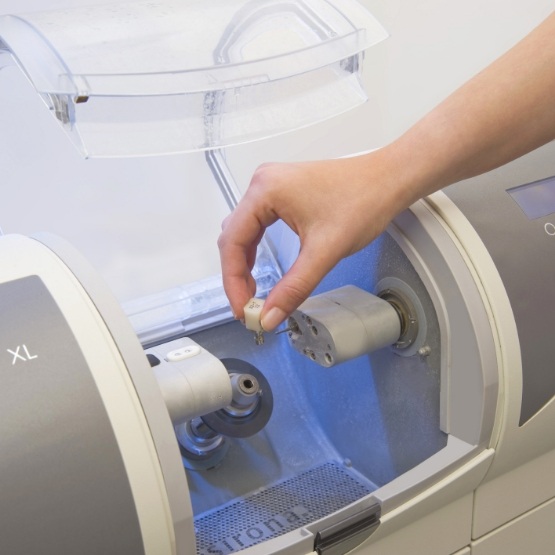 Dentist picking up completed crown from CEREC machine