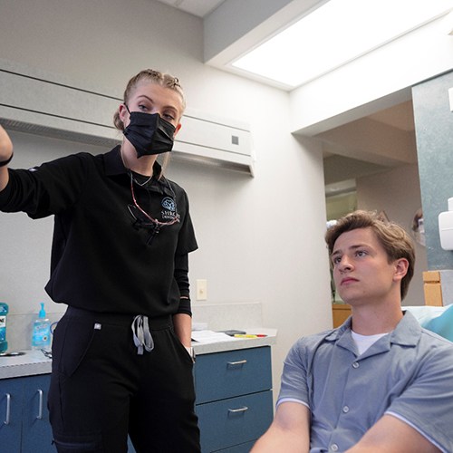 a patient looking at a monitor that a dentist is pointing at