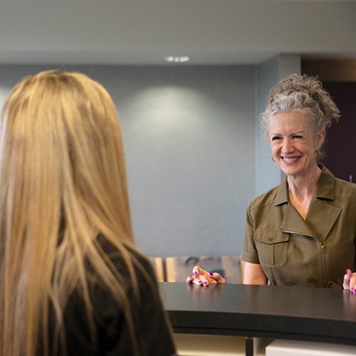 a patient speaking to front desk staff at a dental office