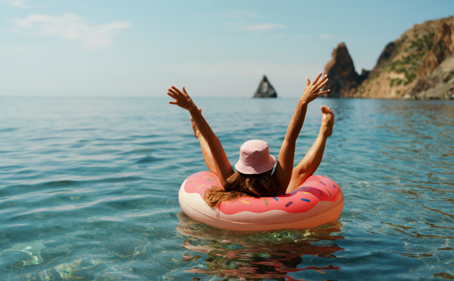 Woman relaxing in pink donut tube floating on lake in the sunshine